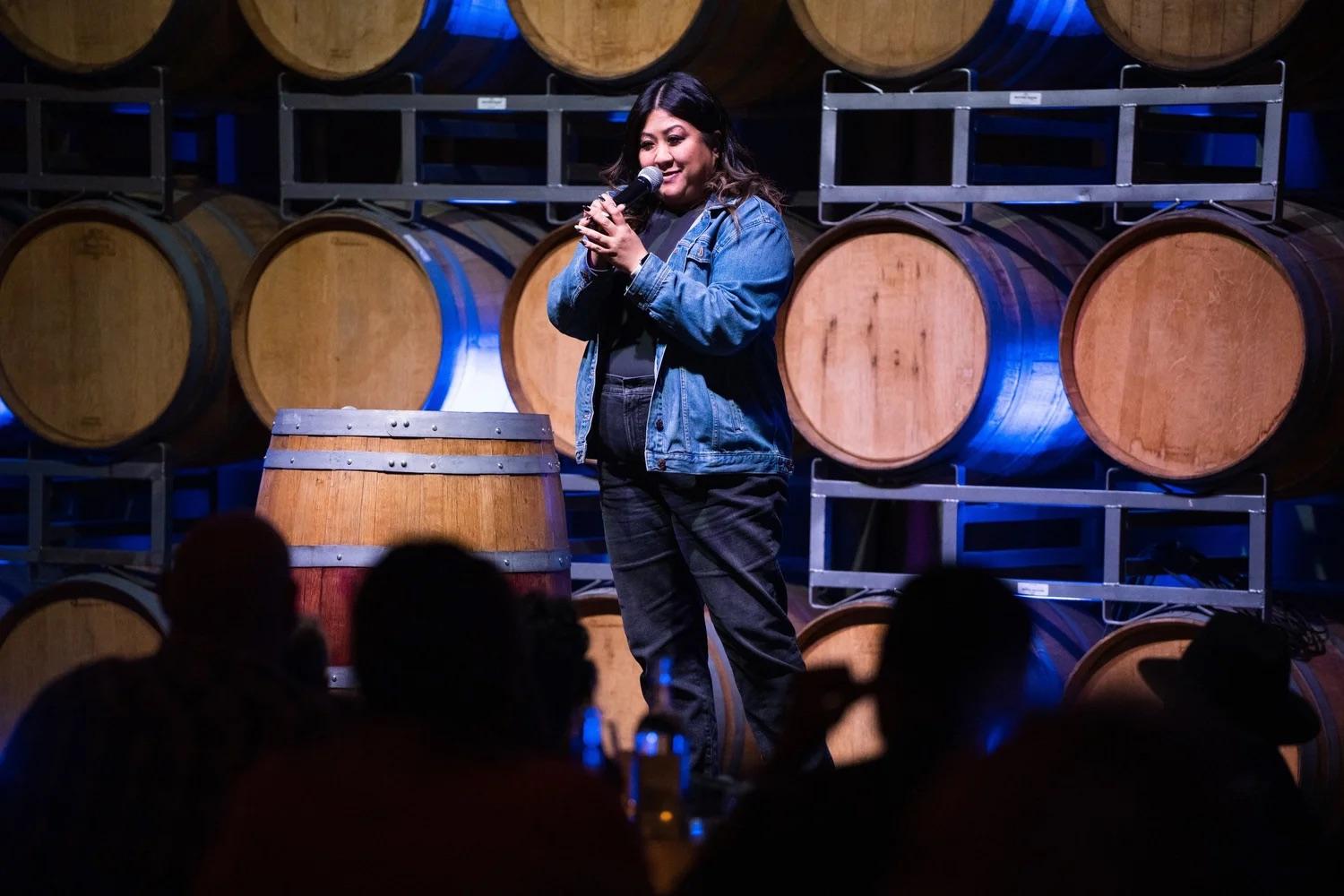 A comedian performing in a barrel room under blue light