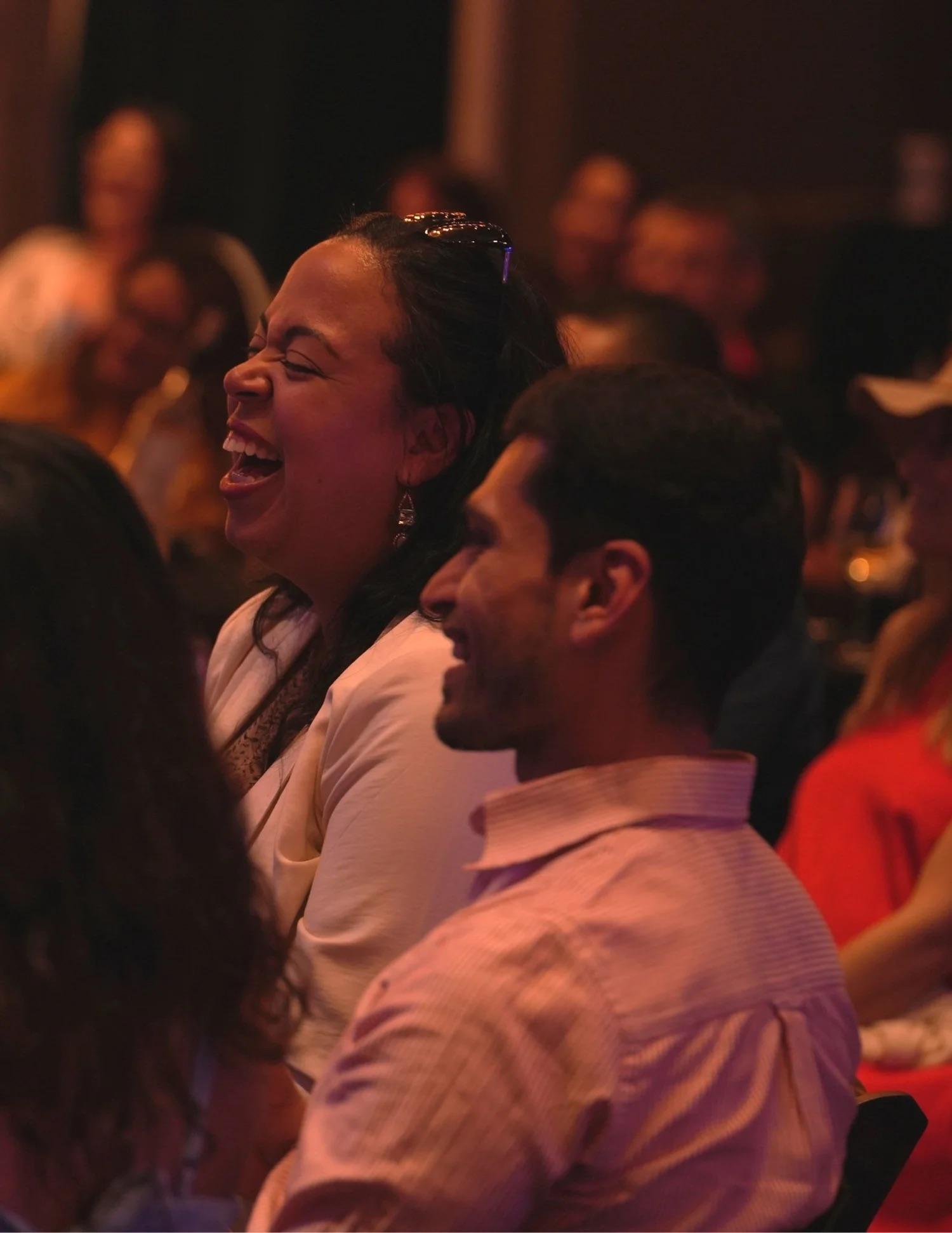 A woman laughing with friends in the audience
