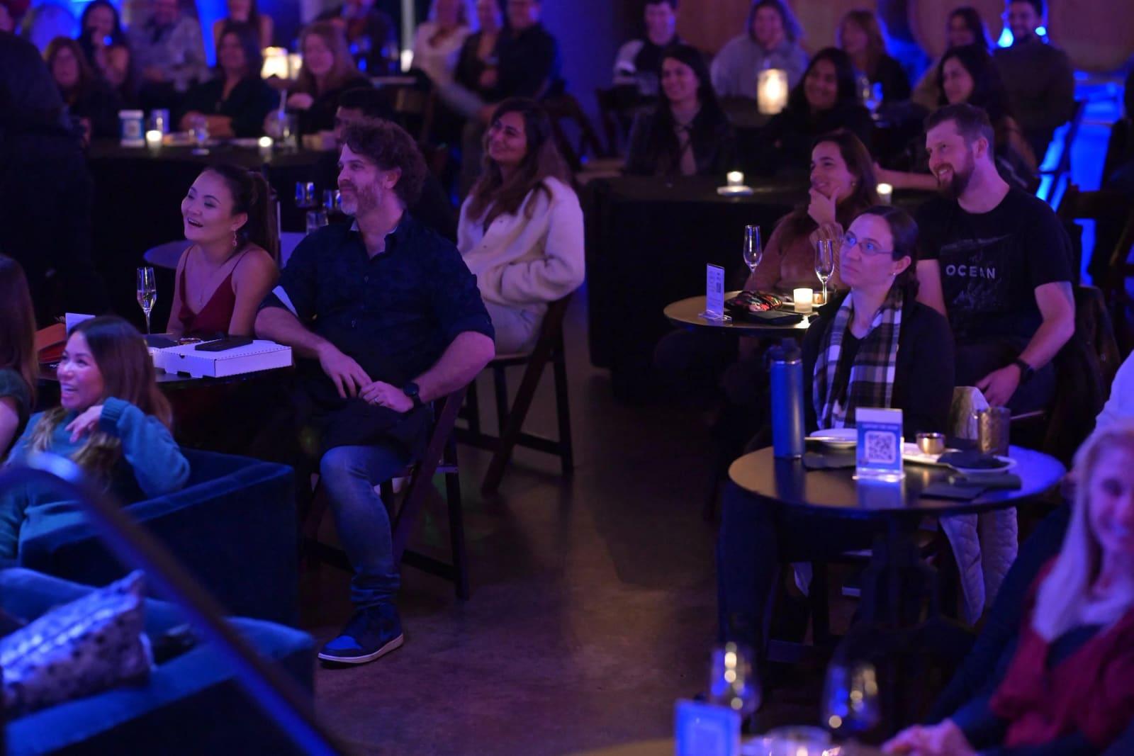 A full room of guests at candlelit tables watching a show in a winery